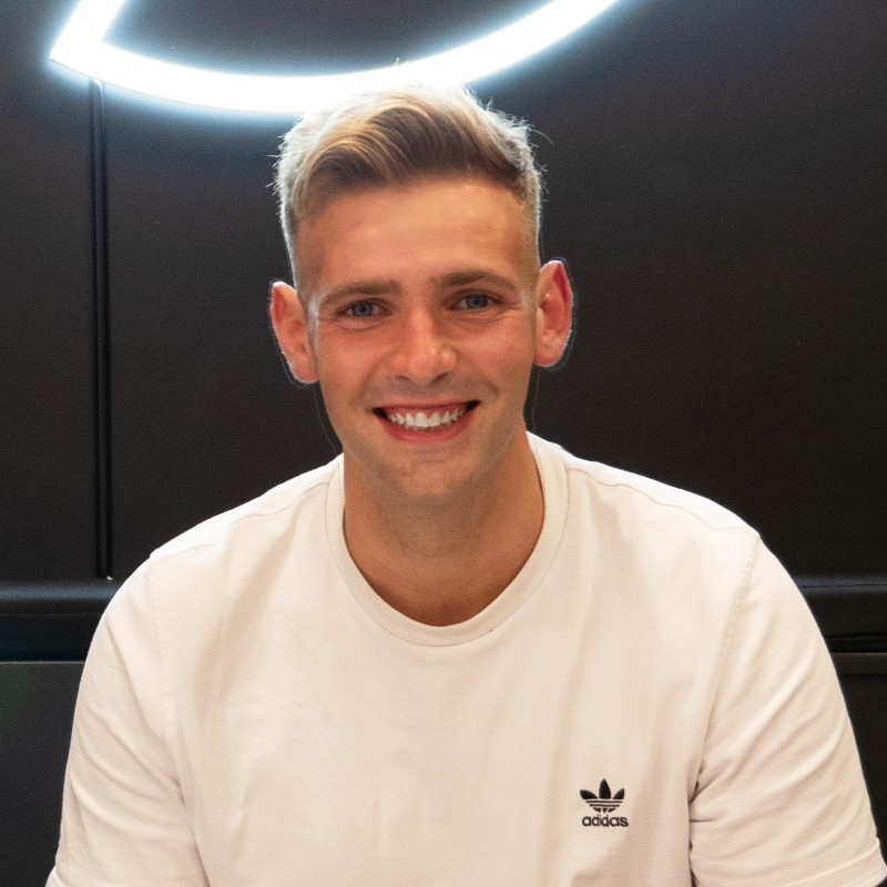 James Hayward-Browne, a young white man smiling towards the camera with a ring of light above him.